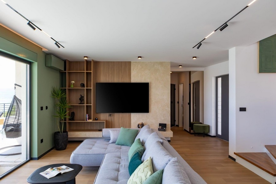 Öppen vardagsrumsdel med TV-vägg och designtrappa