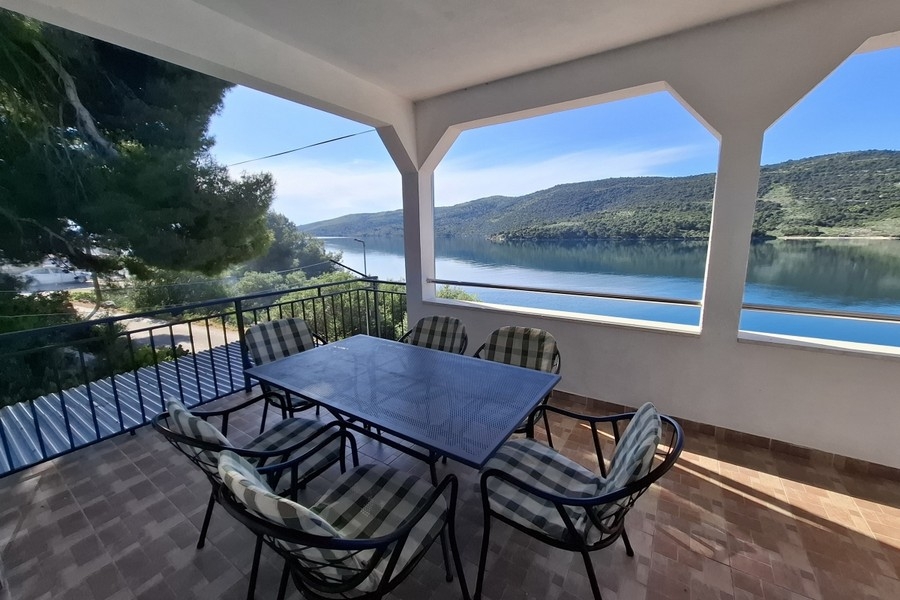 Täckt uteområde med matbord och havsutsikt