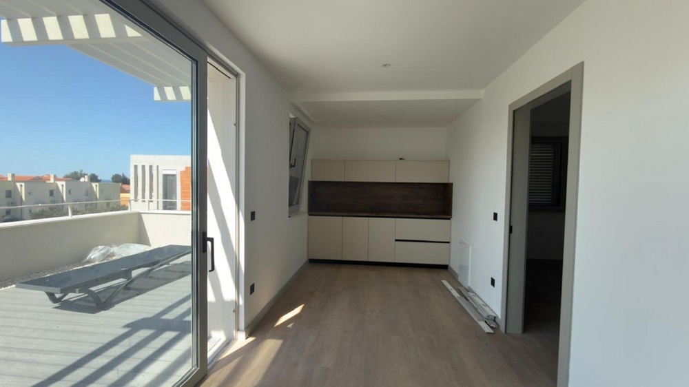 Ljust vardagsrum med öppet kök och tillgång till terrass