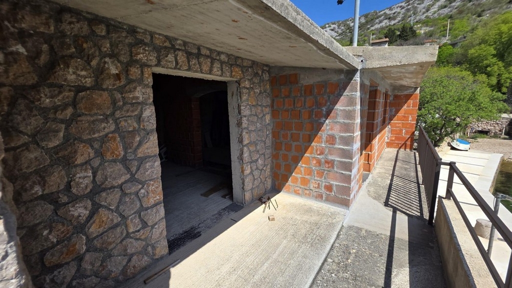 Uteplats med naturstensmur och täckt terrass