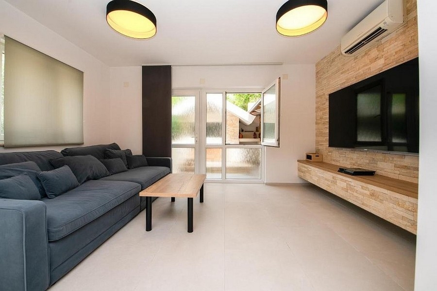 Modernt vardagsrum med soffa, TV-vägg och utgång till altan