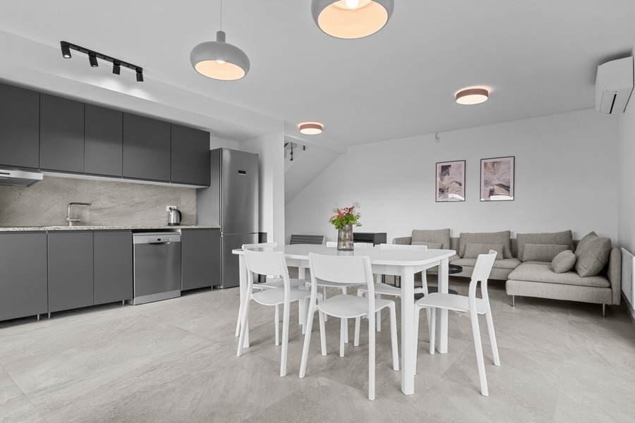 Ljust vardagsrum med soffa och integrerat kök i öppen planlösning