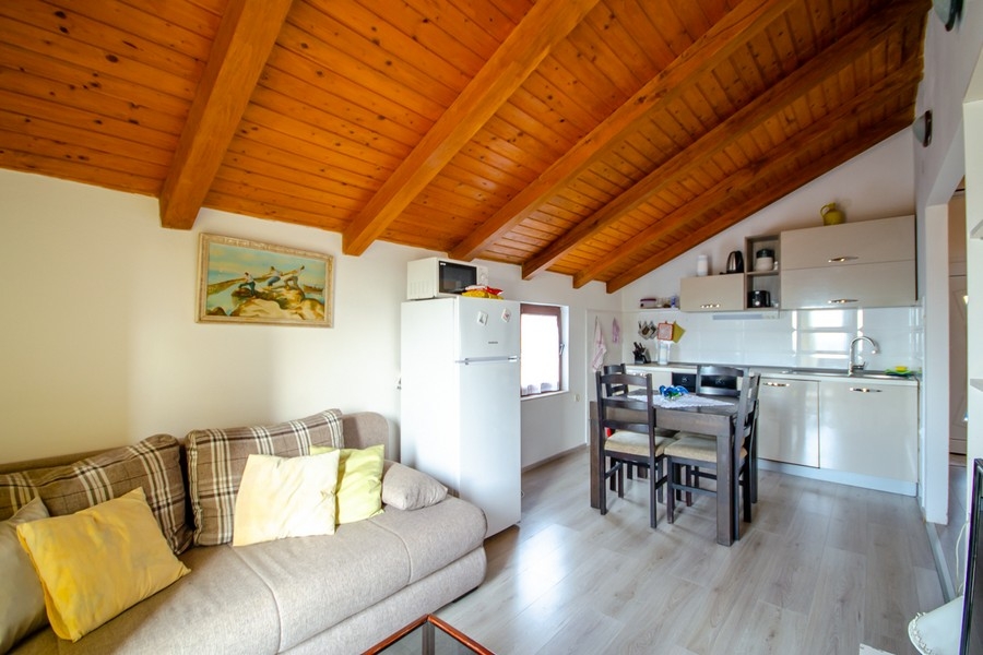 Vardagsrum och matplats med öppet kök och takbjälkar i trä