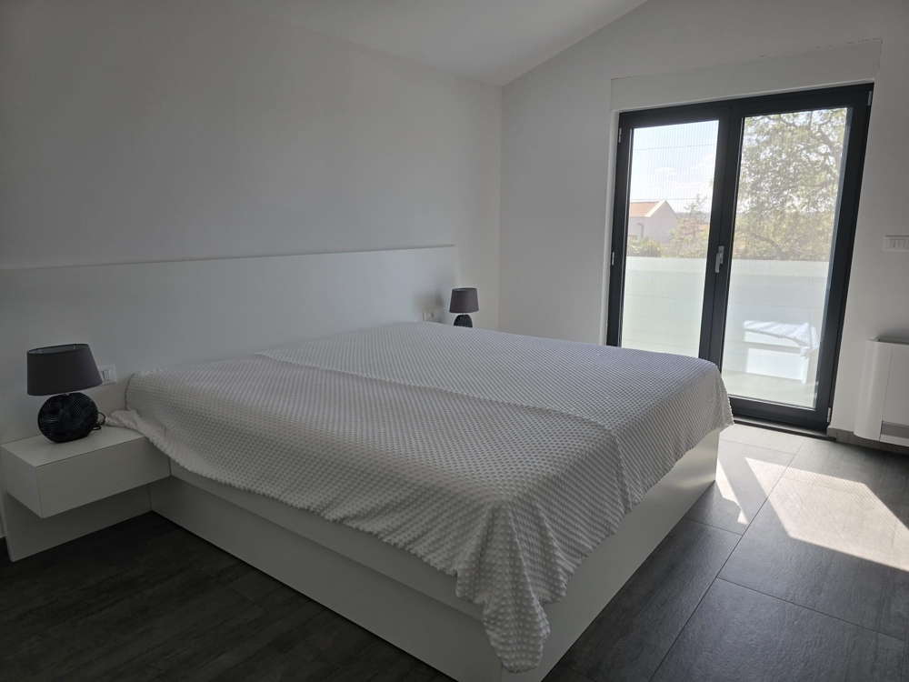 Ljust vardagsrum med stort fönsterfront och utgång till altan