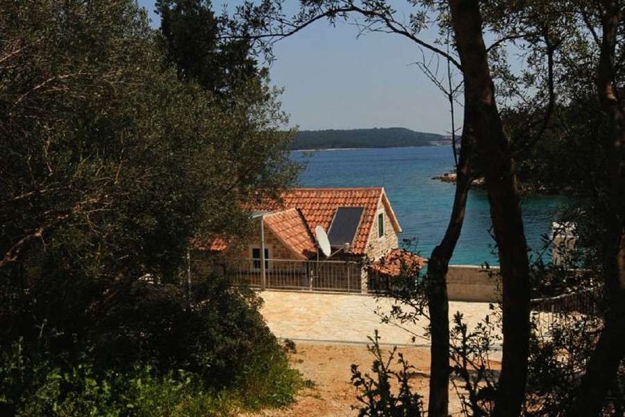 Stenhus med havsutsikt mellan träd