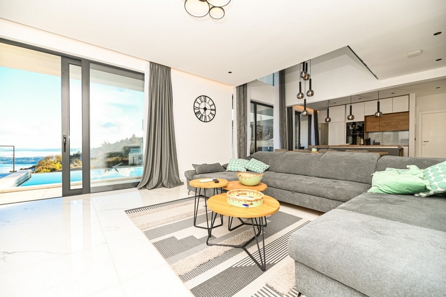 Vardagsrum med stora fönster och utsikt över poolen