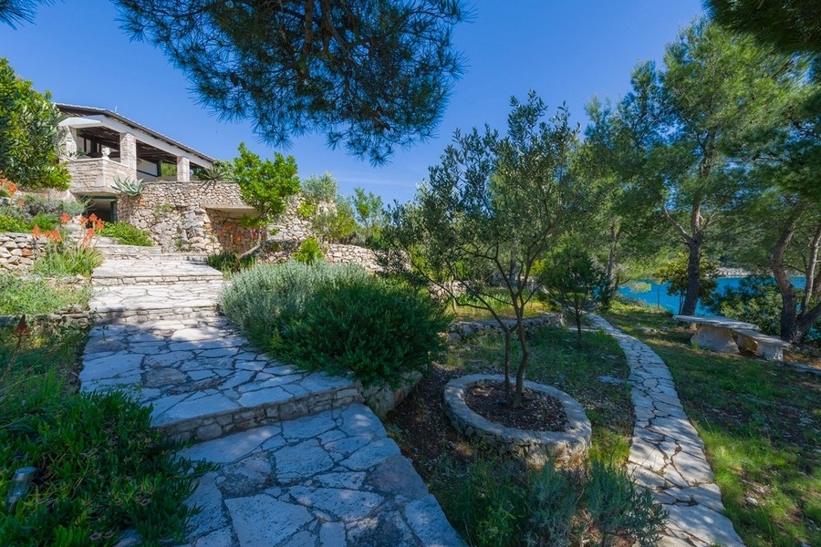 Naturstensterrass med palmer och kustutsikt