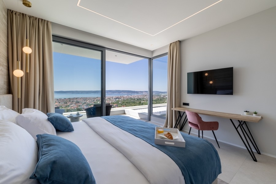 Modernt sovrum med glasfront och kustpanorama