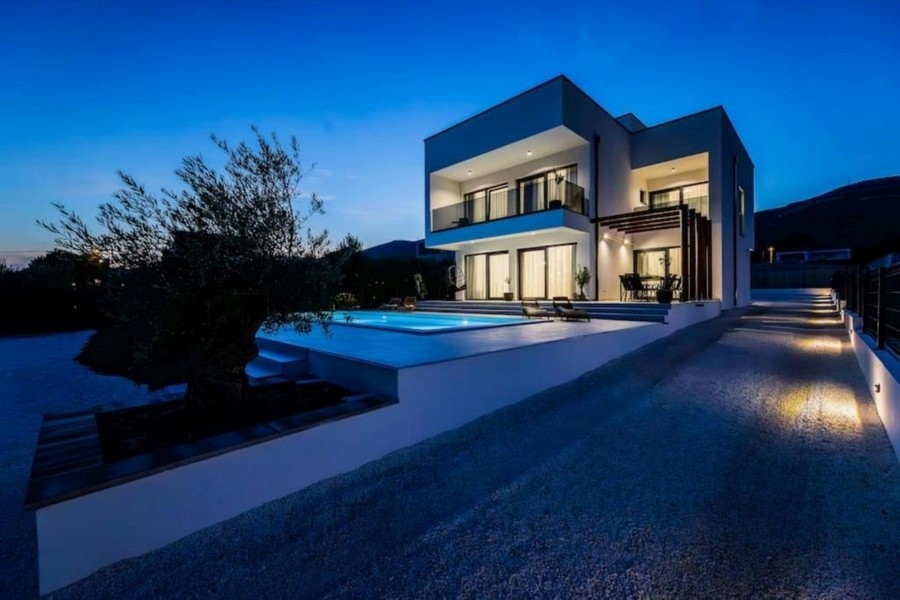 Modern villa på natten med upplyst pool