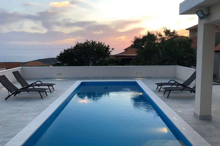 Pool med solstolar och solnedgång
