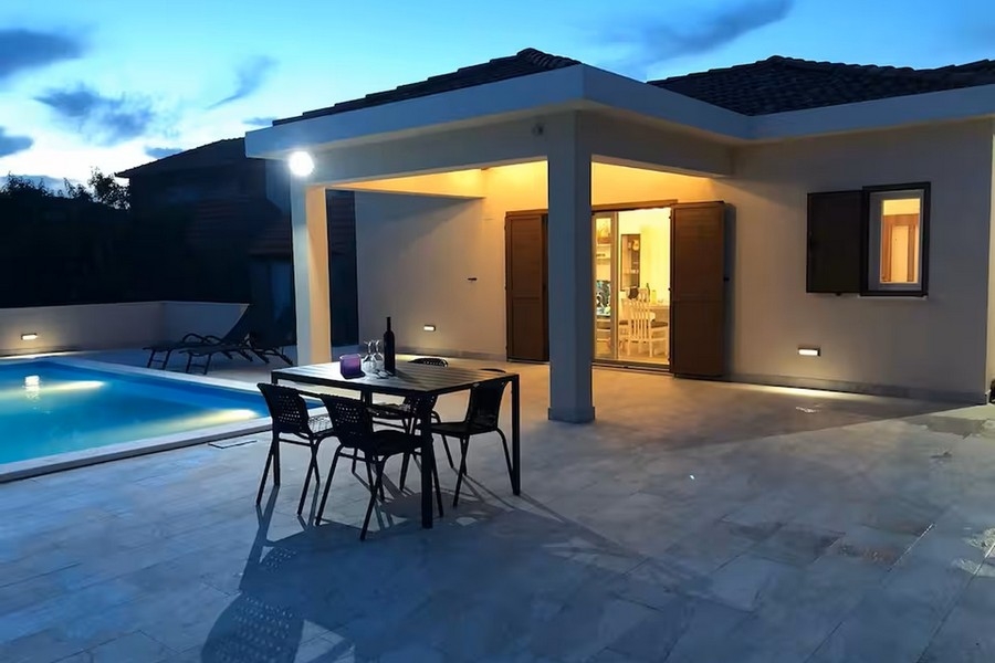 Bungalow på kvällen med pool och täckt terrass