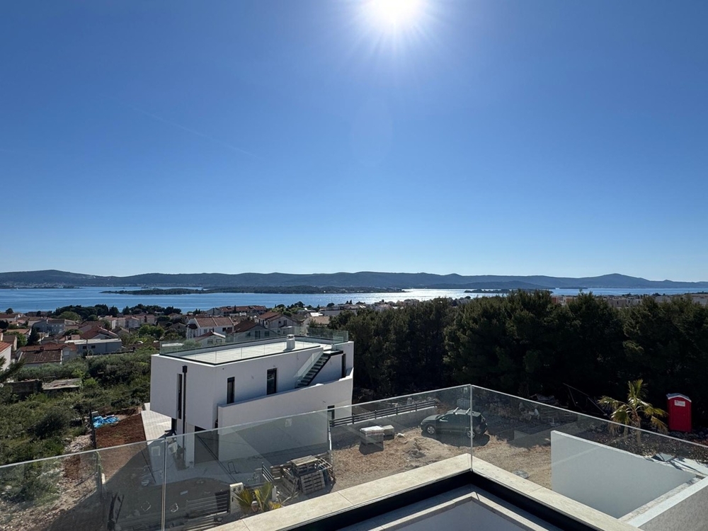 Sidovy av modern villa med palmträd och trädgård