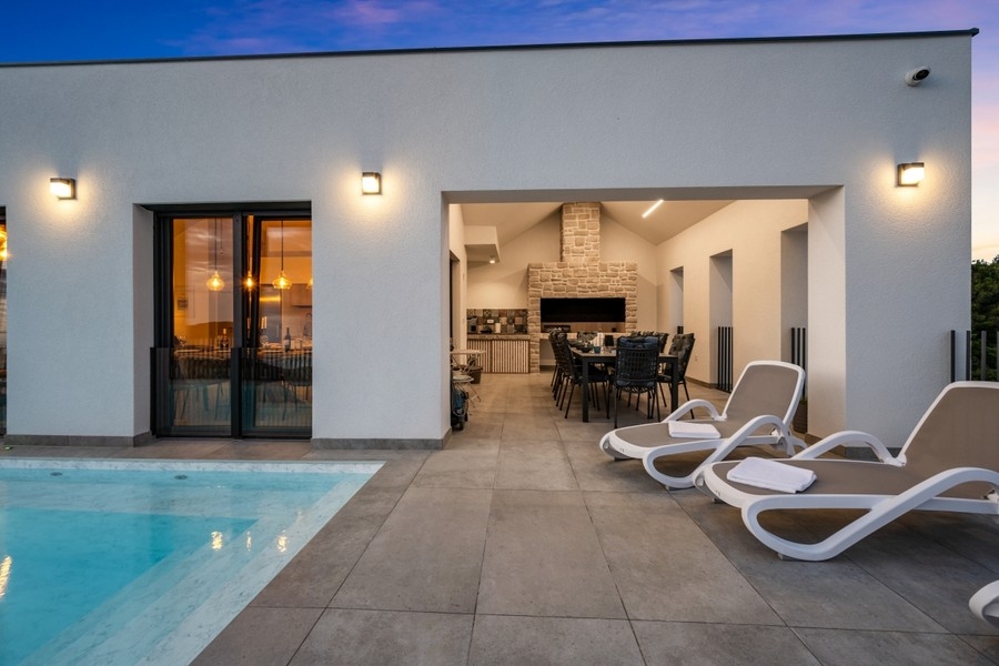 Täckt terrass med solstolar och pool på kvällen