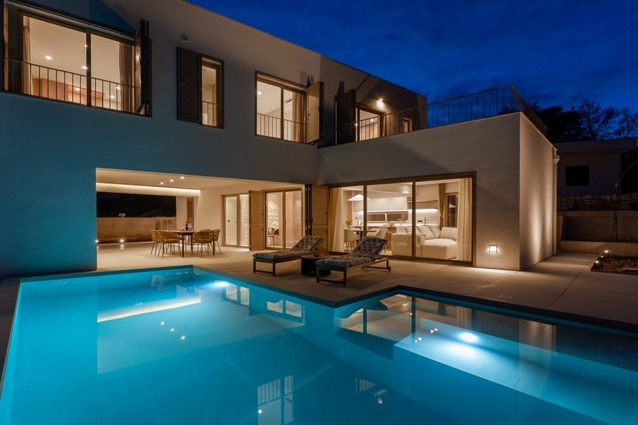 Upplyst villa med pool i skymningen
