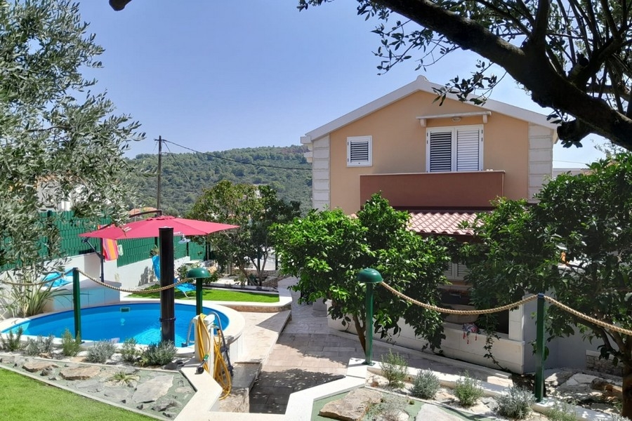 Exteriör vy av huset med trädgård och pool
