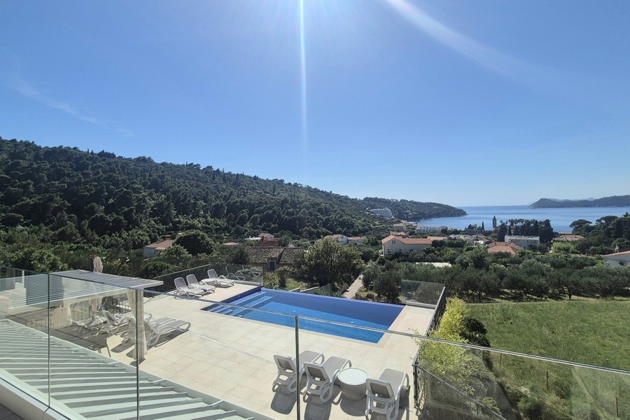Poolterrass med solstolar och havsutsikt