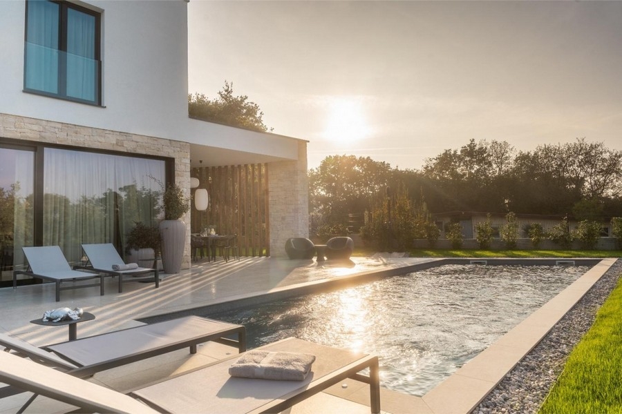 Pool med solstolar vid solnedgången