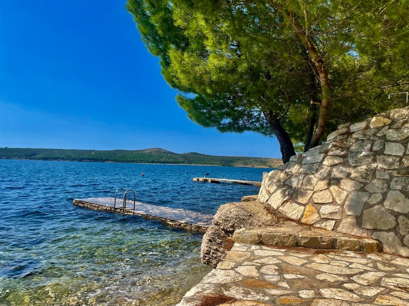 Brygga på vattnet med naturlig stenmur i Kroatien