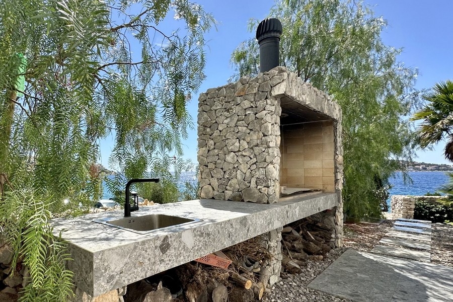 Utomhus spis i tegel med grill och diskbänk vid havet