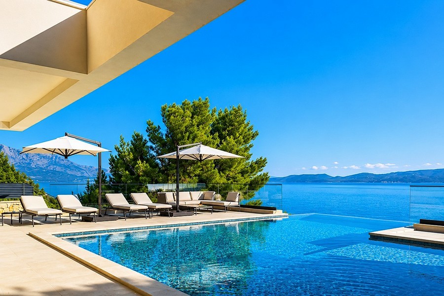 Poolterrass med solstolar och havsutsikt