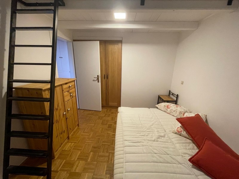 Sovrum med trämöbler och stege till galleriet