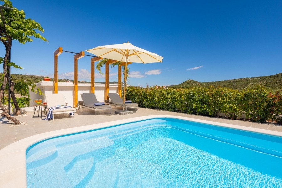 Pool med solstolar och pergola
