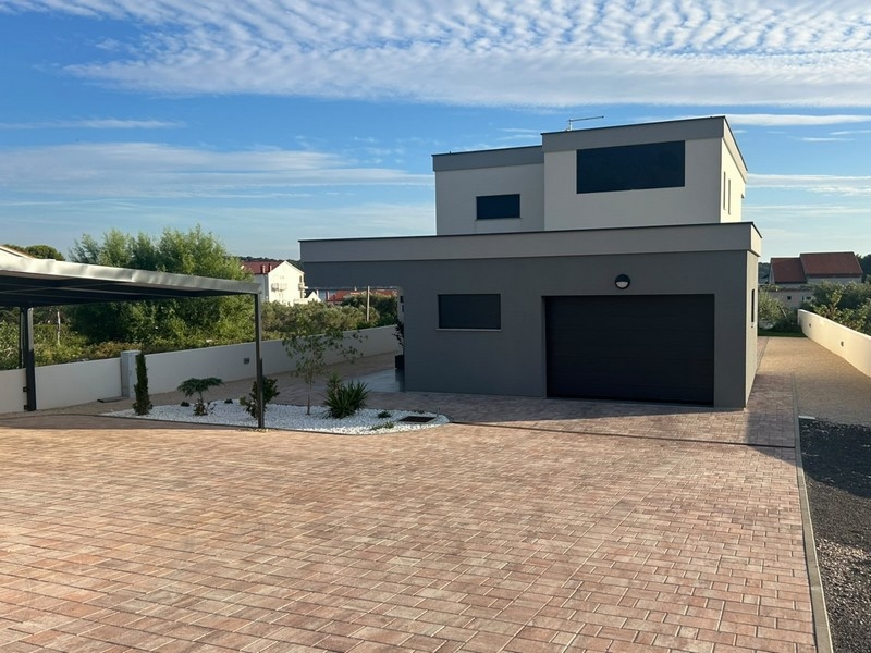Vy över hus med garage och stenlagd förgård