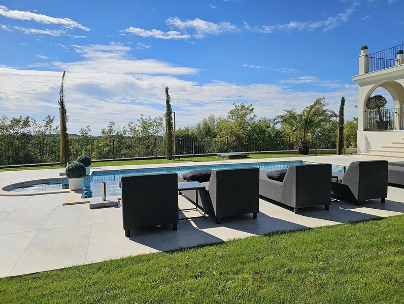 Poolterrass med loungemöbler och gräsmatta