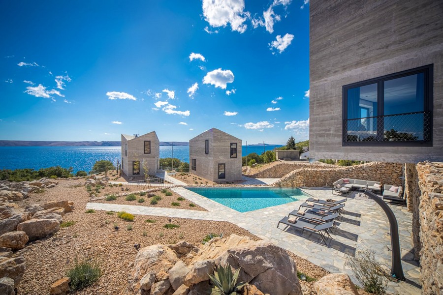 Poolterrass med solstolar och havsutsikt