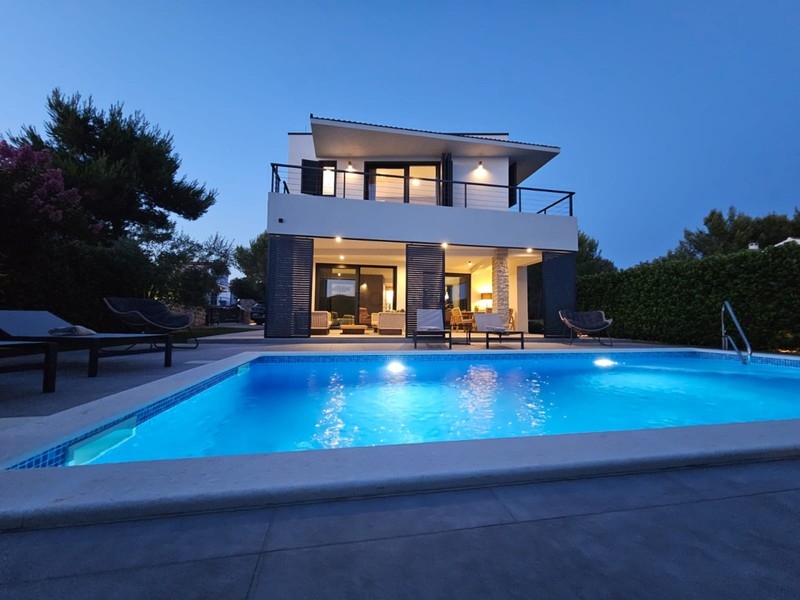 Upplyst villa med pool på kvällen