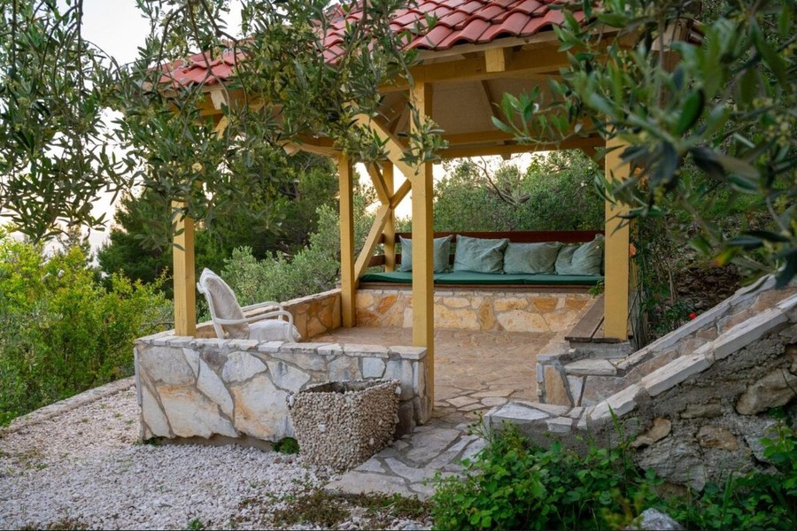 Pergola med bänk mellan olivträd