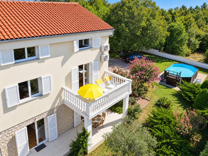 Balkong med solstolar över trädgården med pool