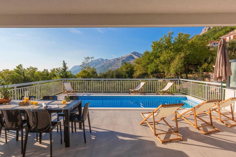 Pool med solstolar och utsikt mot bergen
