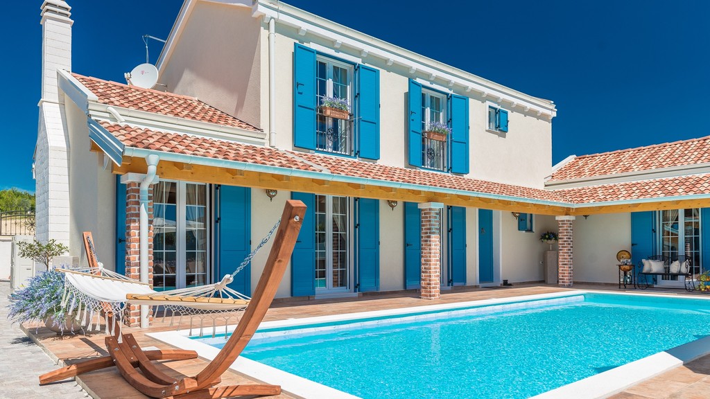 Villa med blå fönsterluckor och pool