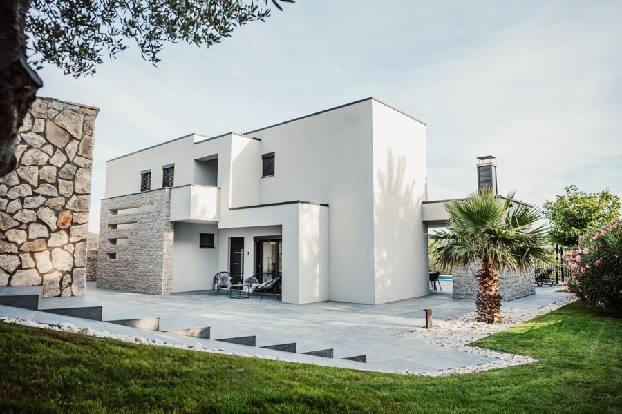 Modern villa med gräsmatta och stenfasad