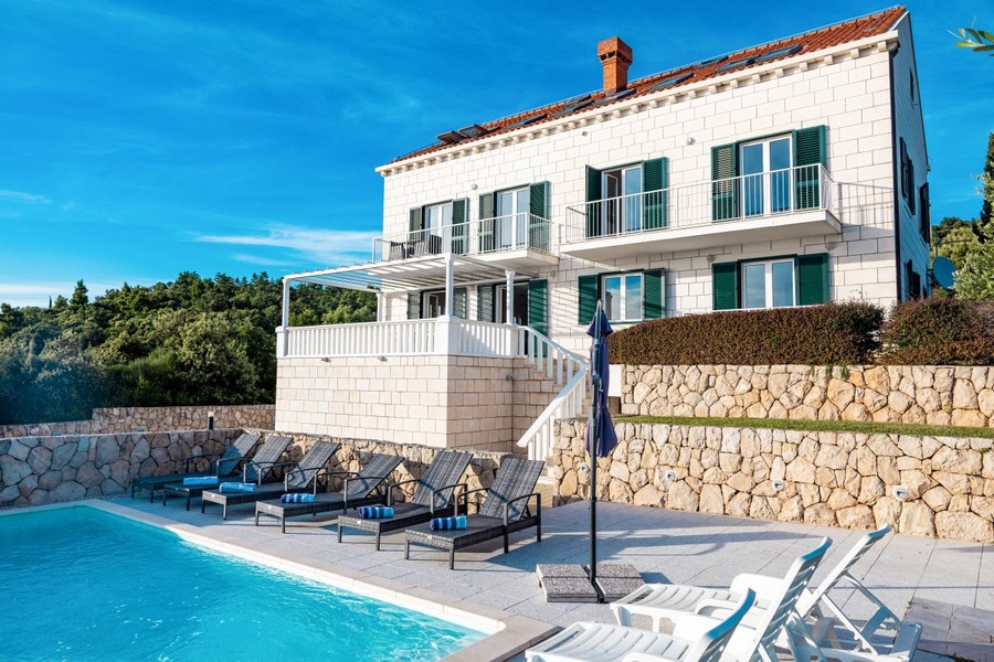 Stenvilla med pool och solstolar