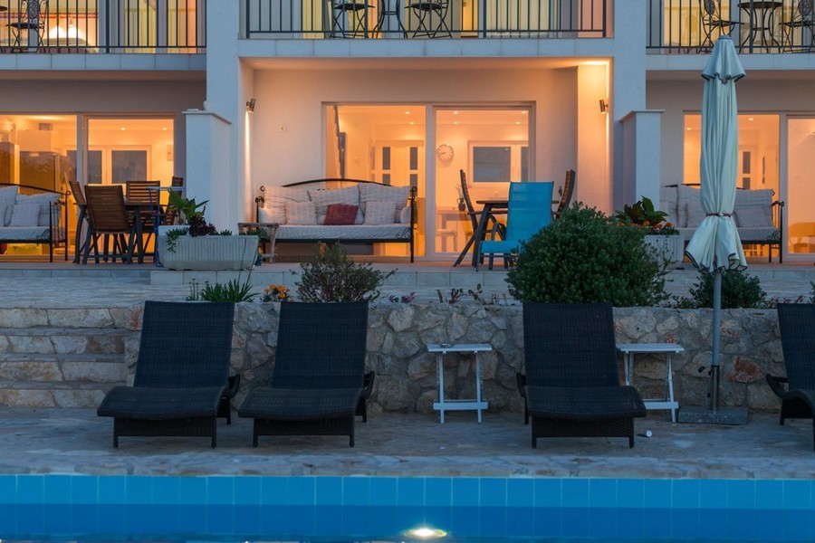 Terrasser till bostadsenheterna med solstolar vid poolen