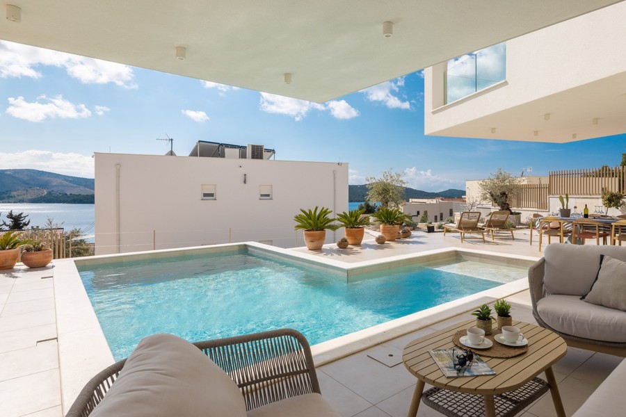 Täckt terrass med utsikt över pool och havet