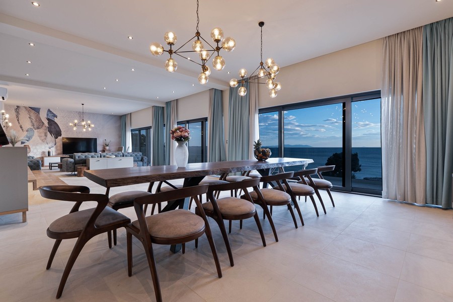 Långt matbord framför glasfasaden mot havet
