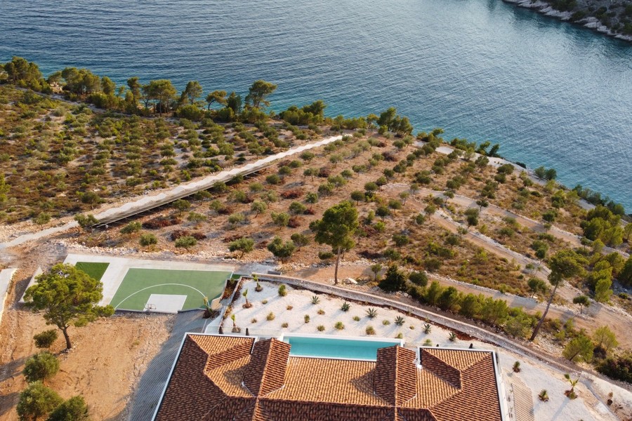 Flygfoto över olivlund mellan villa och hav