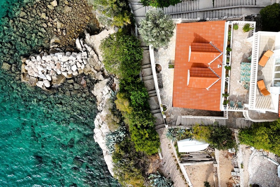 Flygfoto över hus och trädgård vid klippkusten
