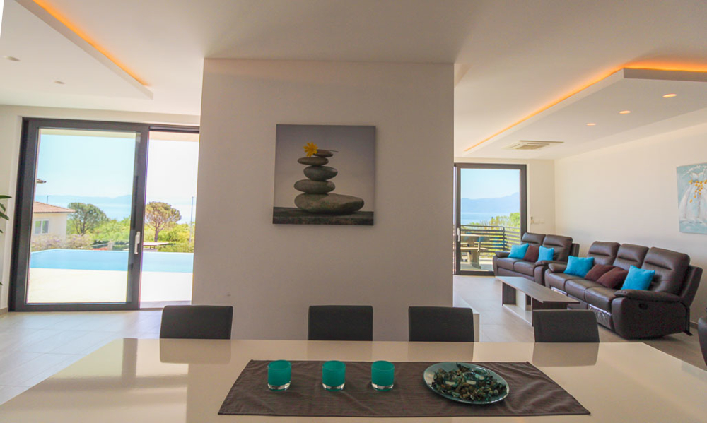 Utsikt över matsalen med utsikt över vardagsrummet med stora fönster och utsikt över infinitypoolen.